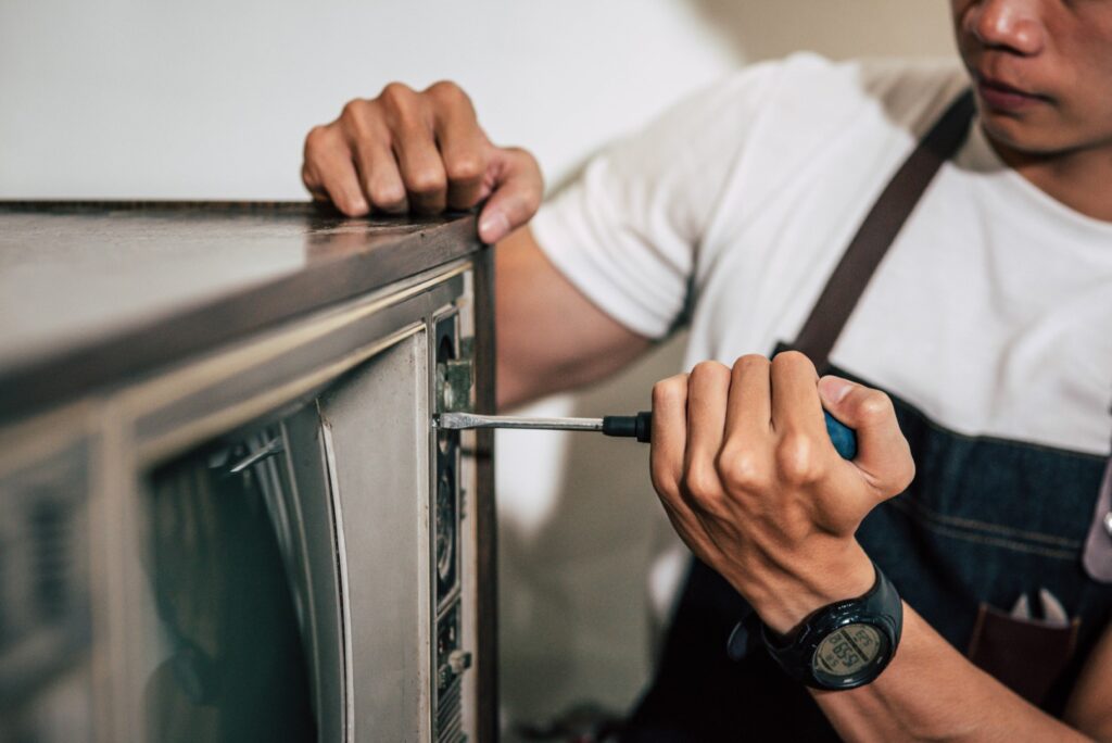 mechanic uses screwdriver tighten screws tv