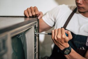 mechanic uses screwdriver tighten screws tv